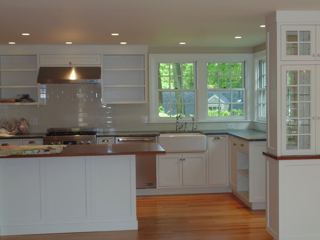 A kitchen with white cabinets and wood floors.